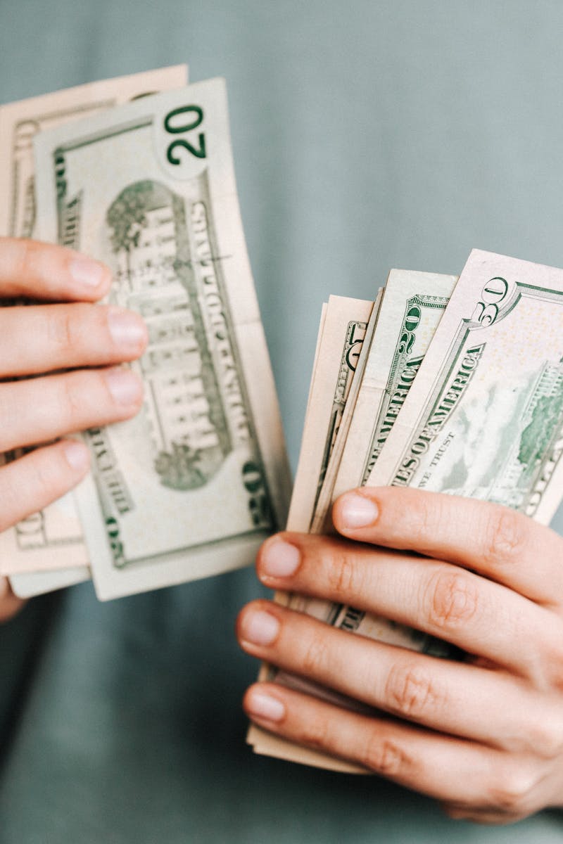 Close-up of a person counting US dollar bills indoors. Financial concept.